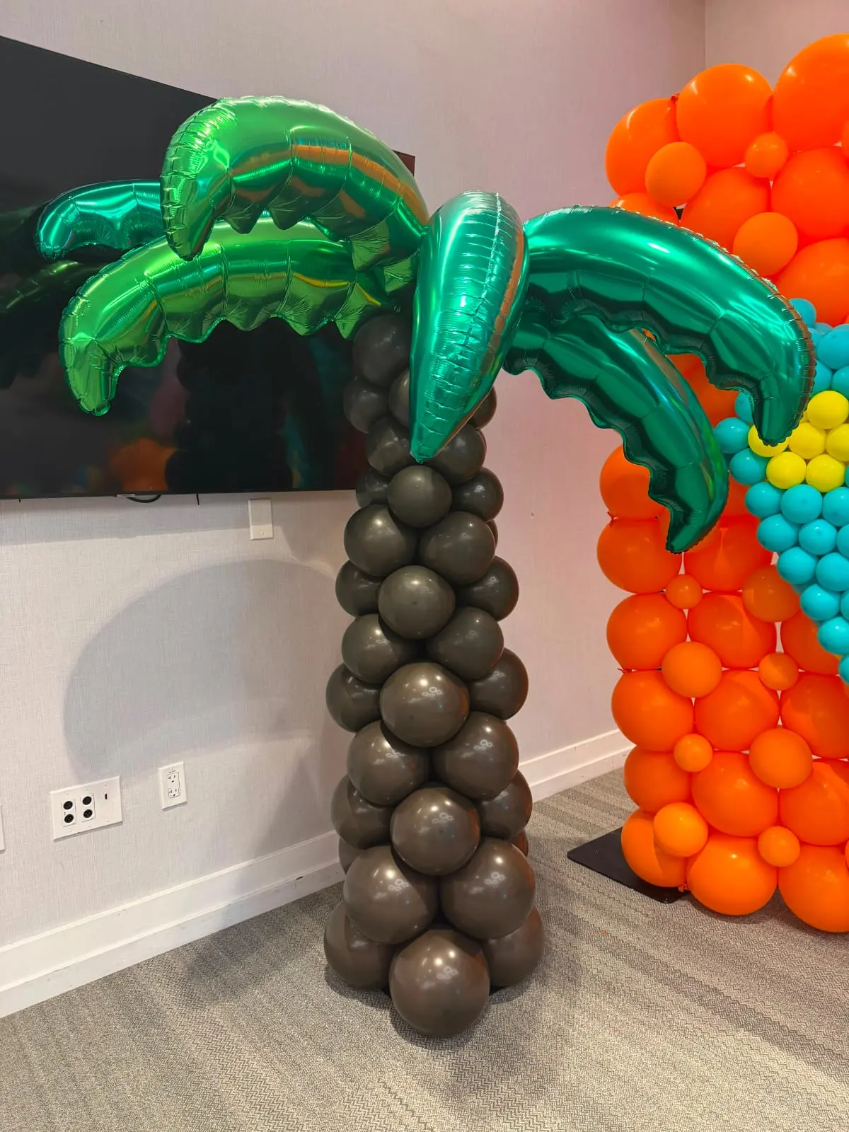 Balloon palm tree structure with green fronds and brown trunk at an event