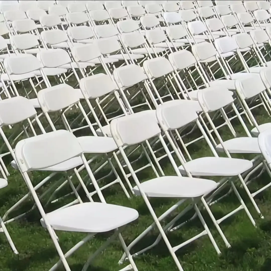 Rows of white folding chairs set on grass for event seating