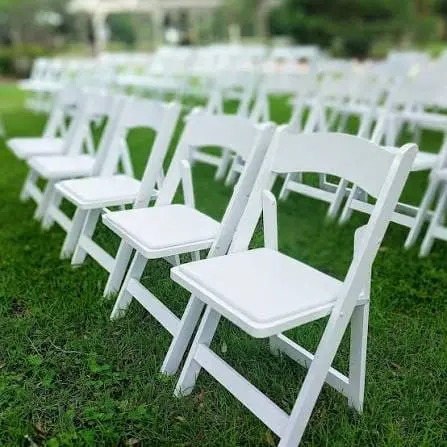 White resin folding chairs with padded seats arranged outdoors