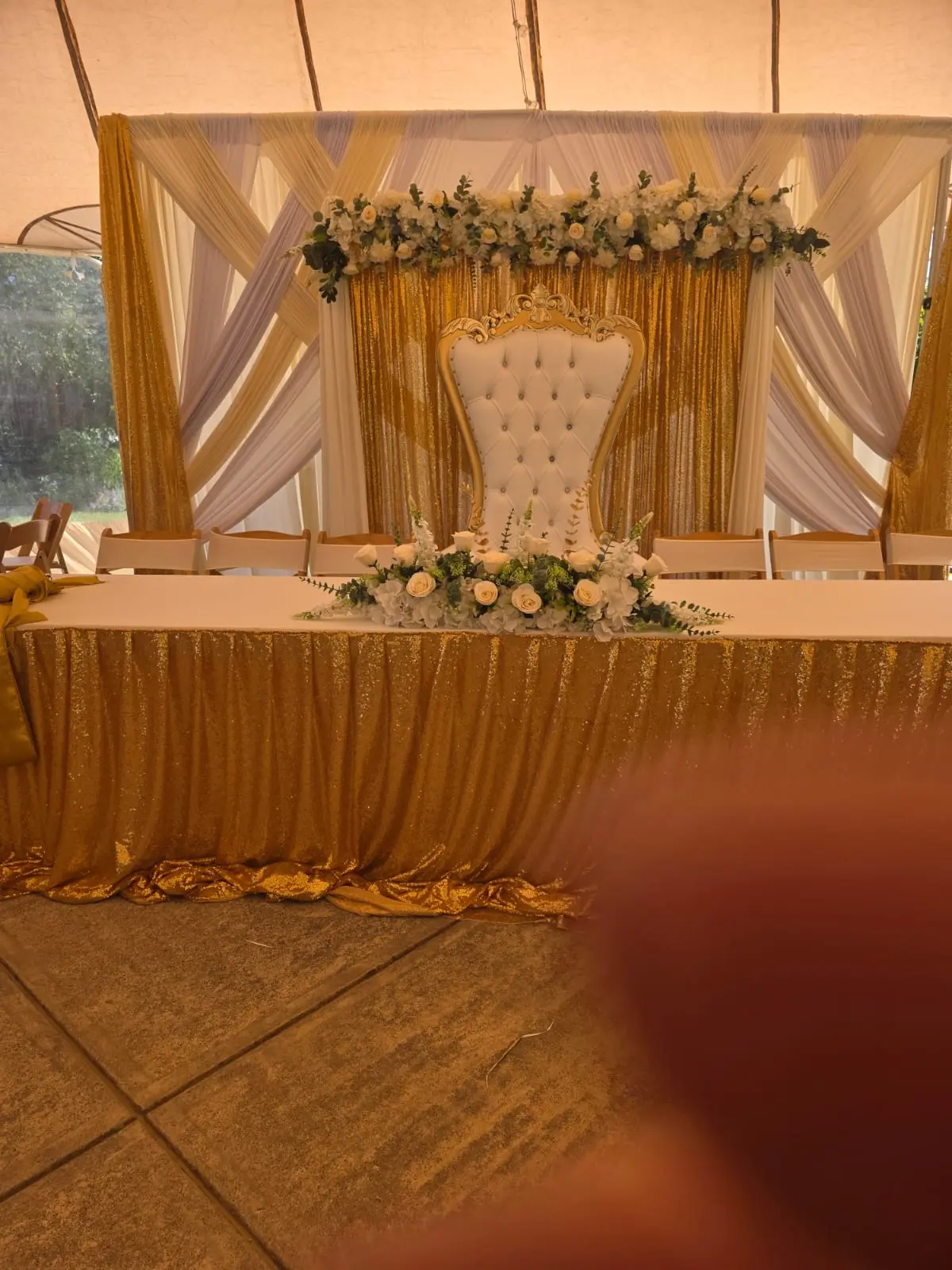 Gold and white head table under a tent with sequin skirting, florals and throne chair