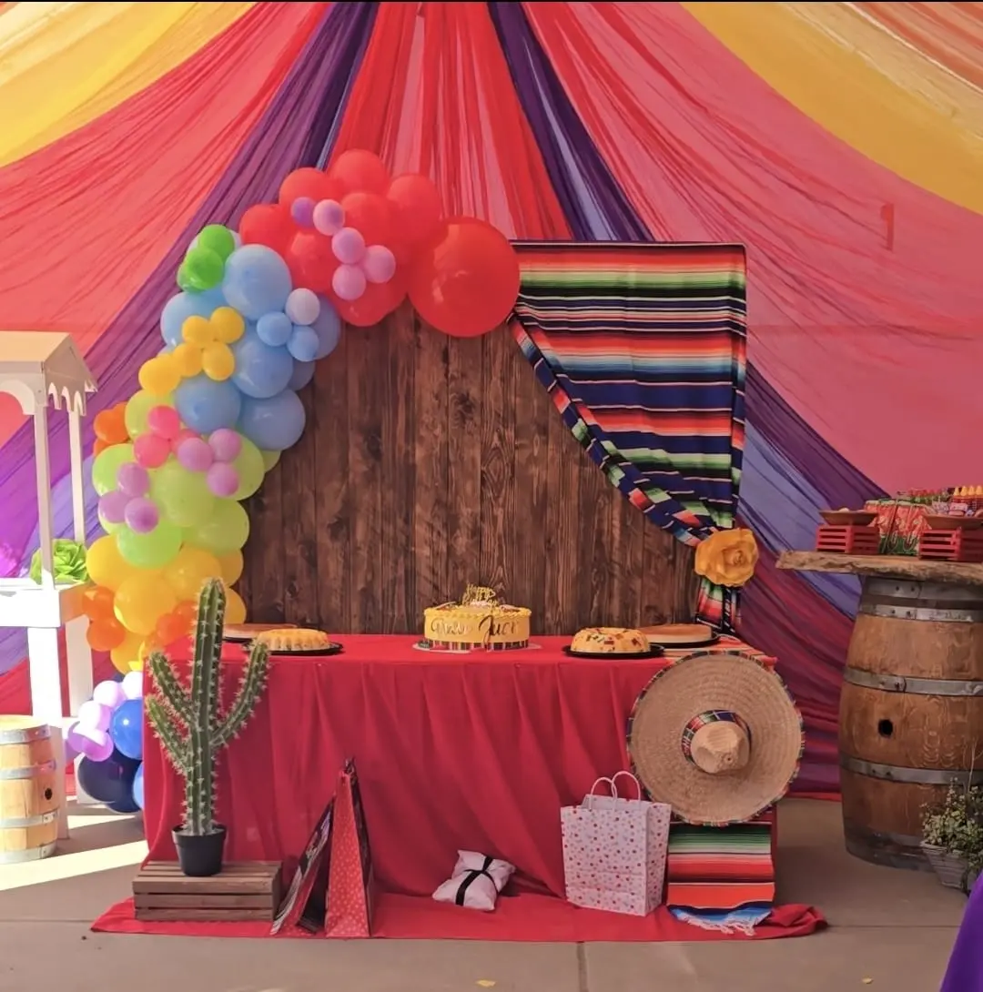 Colorful fiesta backdrop with a cactus, balloons and a wood panel circle
