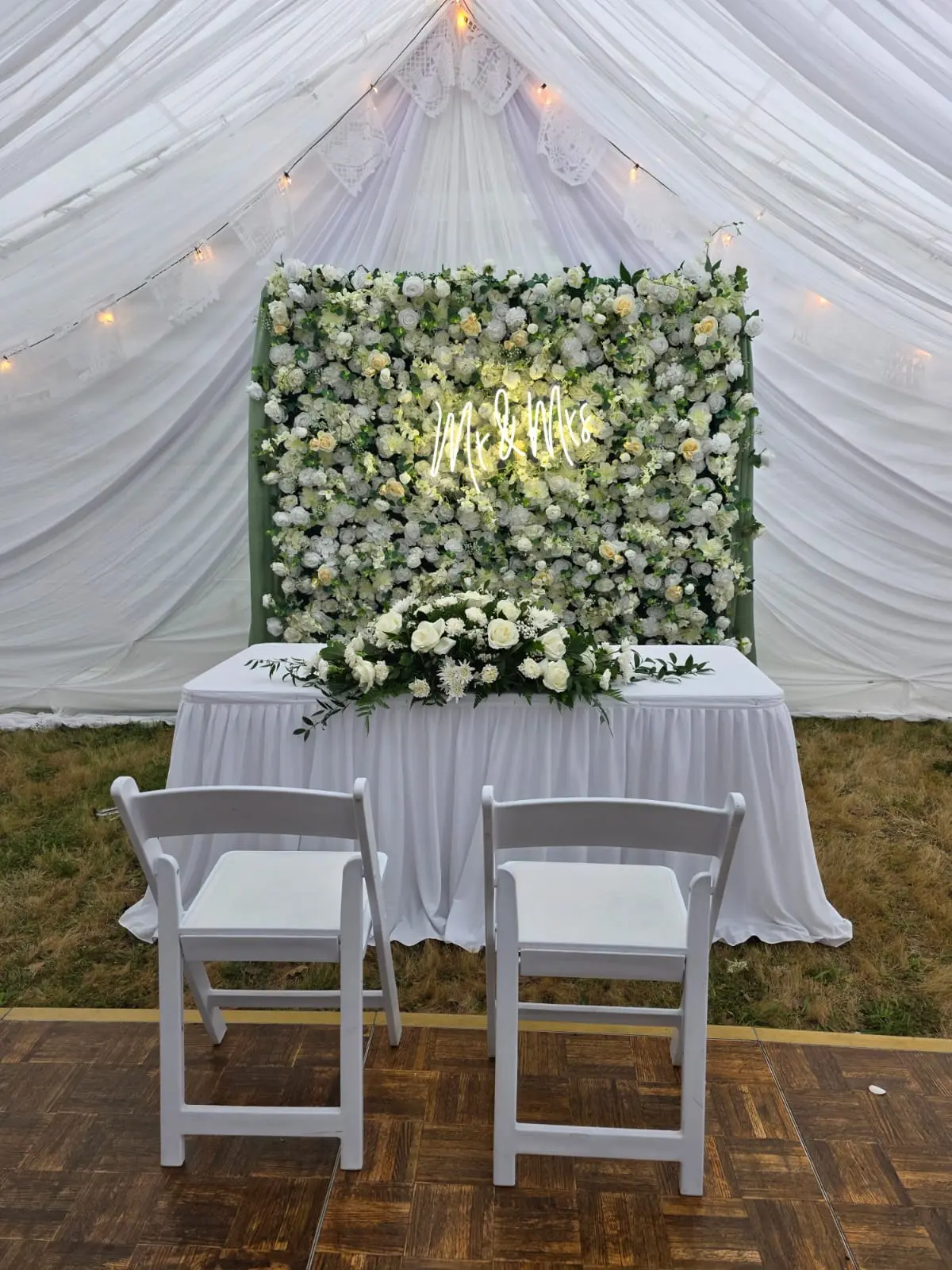 White flower wall backdrop with a neon Mr and Mrs sign