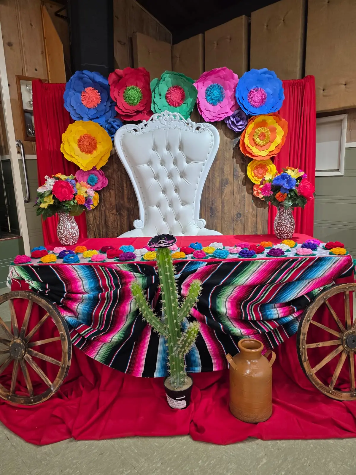 Mexican themed setup with colorful paper flowers and a serape covered table