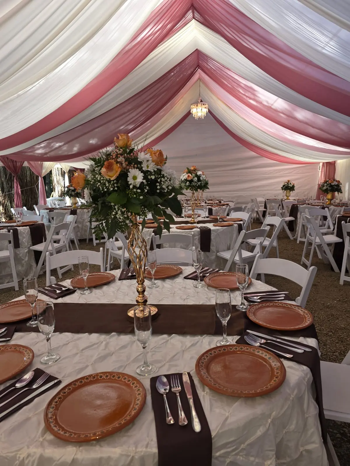 Tables with ivory linens, brown runners, clay chargers and tall floral centerpieces