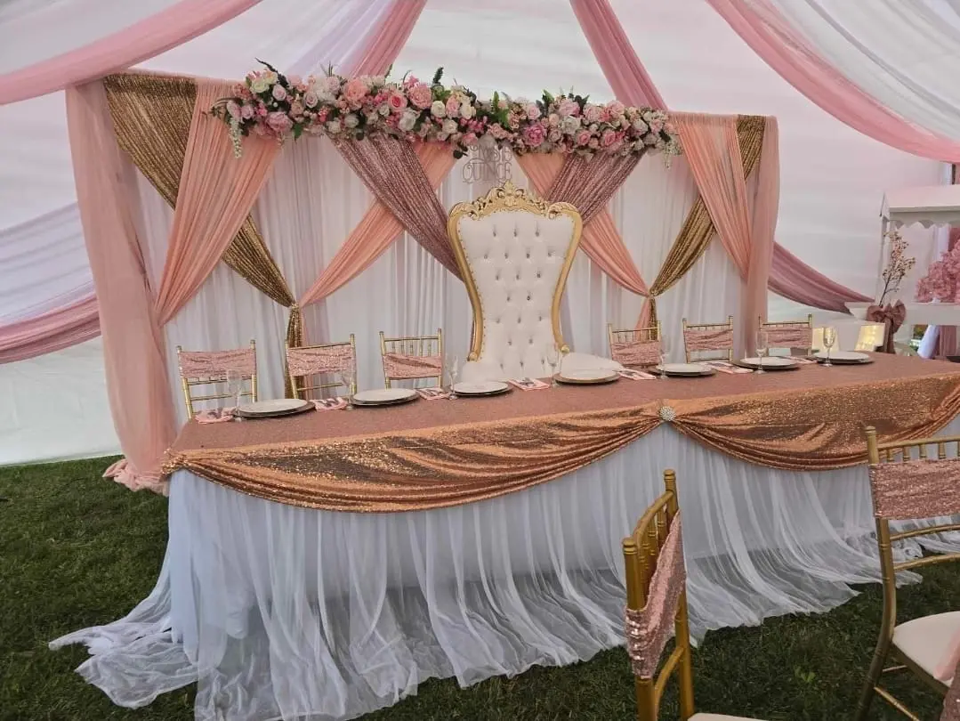 Pink and rose gold quinceañera head table with draping, florals and throne chair