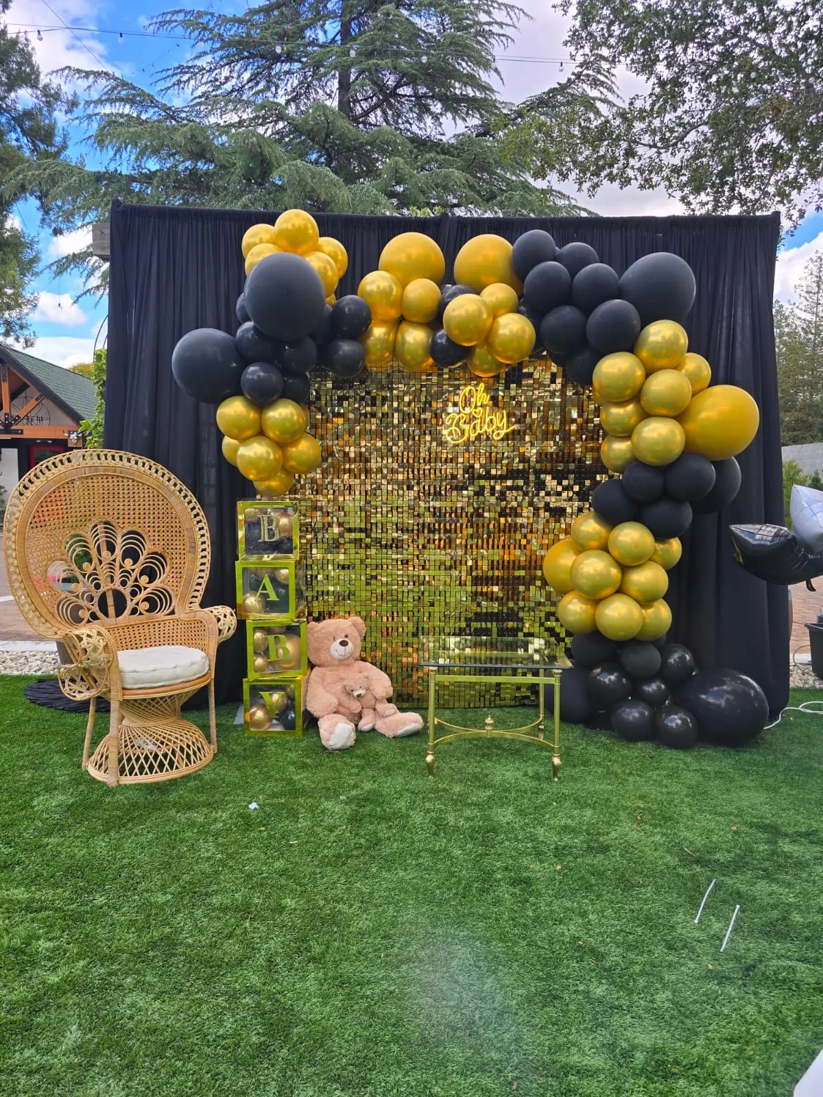 Black and gold baby shower backdrop with sequin wall, balloon arch and Oh Baby sign