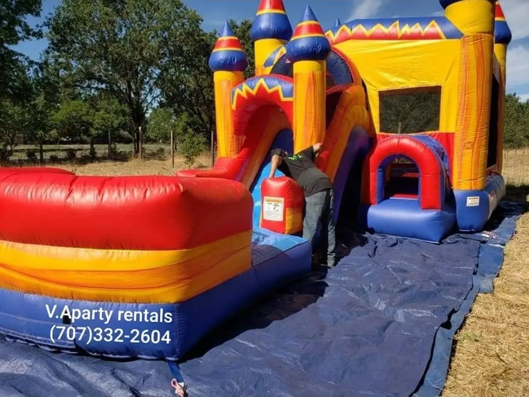 Large castle bounce house with slide and landing lane set up on a grass field