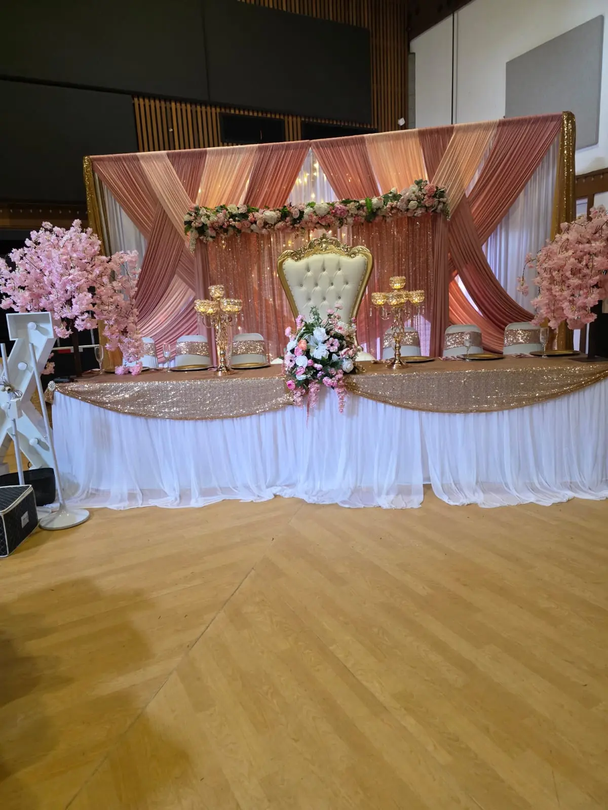 Head table with rose gold sequined cloth and an ornate white throne chair