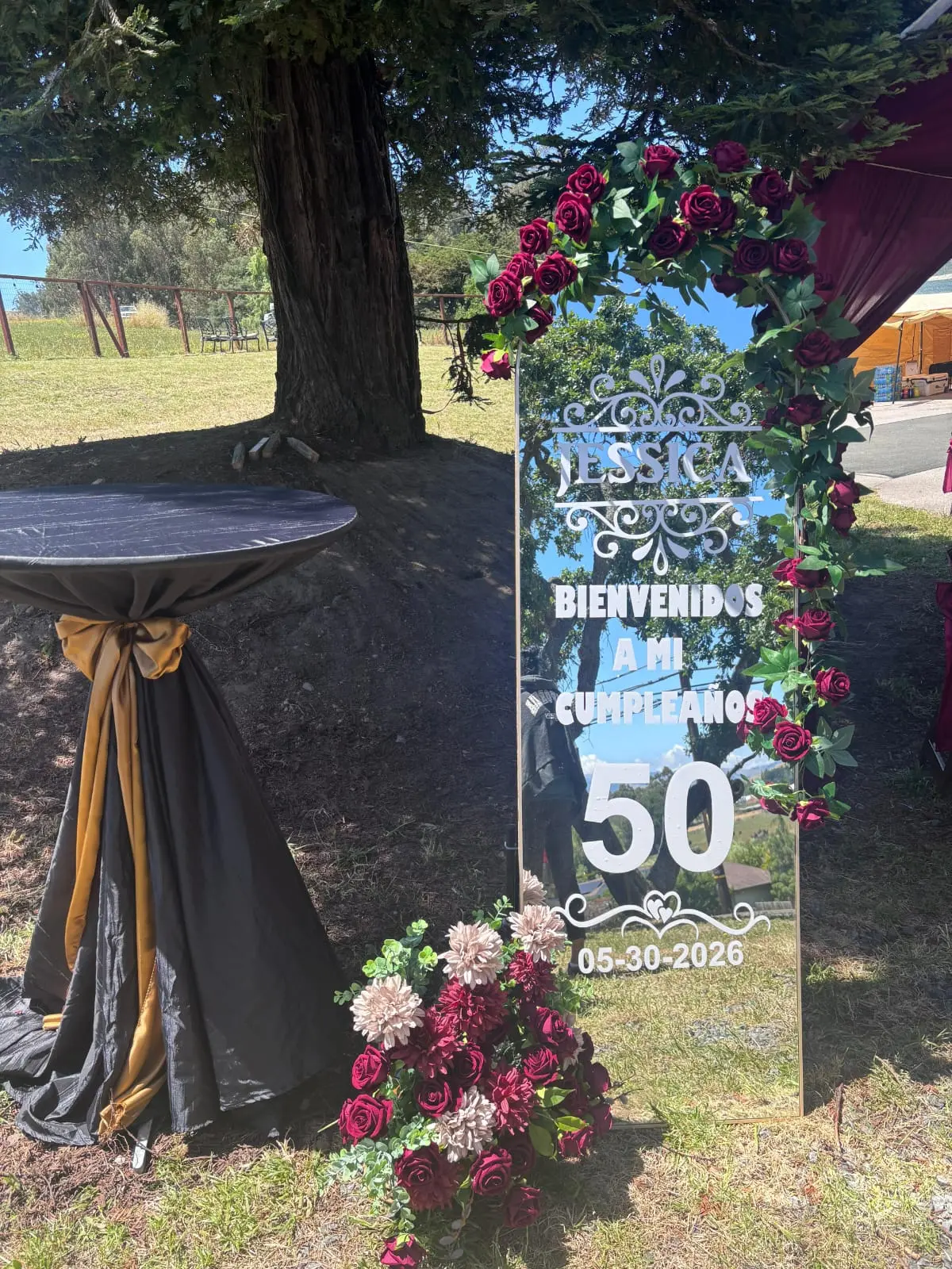Tall mirror welcome sign decorated with red roses for a 50th birthday